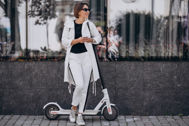 Free Photo young woman riding scotter in town and using phone