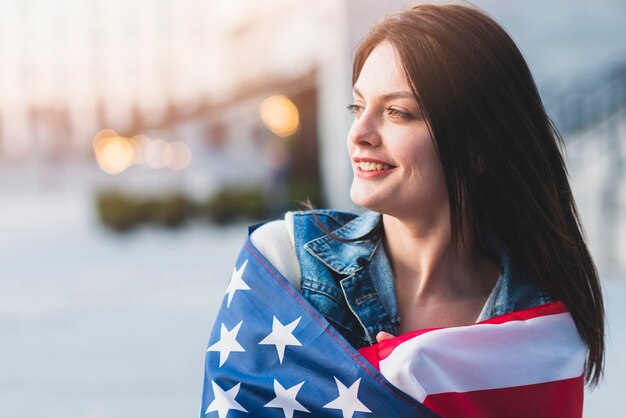 Young woman rolling up in American flag