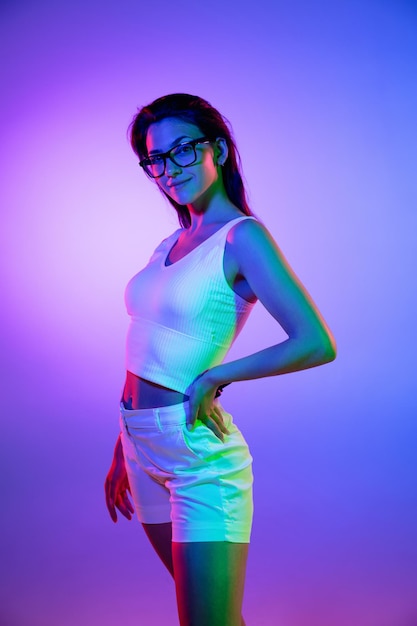 Young woman's portrait on gradient colors studio background in neon Concept of human emotions