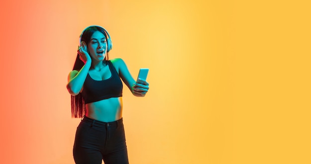 Young woman's portrait on yellow-orange studio in neon light