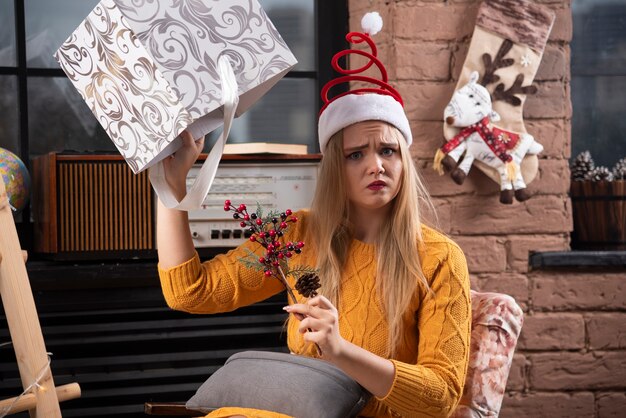 Young woman sadly holding Christmas box.