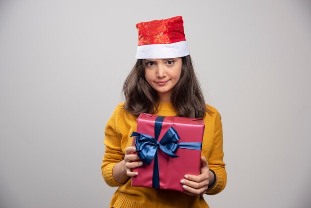 Young woman in Santa Claus red hat with Christmas present . 