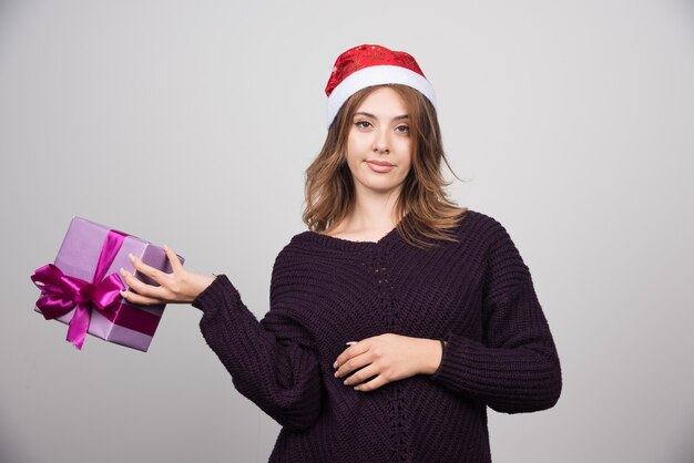 Young woman in Santa hat holding a gift box present.