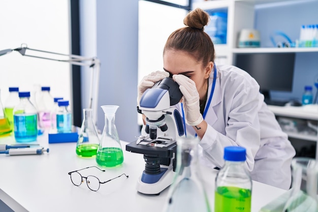 Young woman scientist using microscope at laboratory