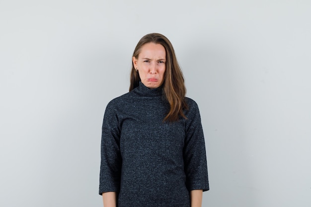 Young woman scowling while crying in shirt and looking offended. front view.