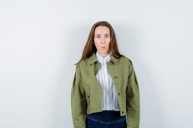 Young woman in shirt, jacket looking at camera and looking puzzled , front view.