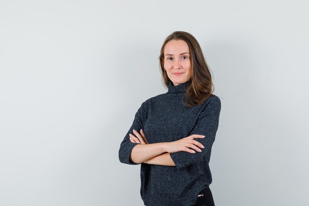 Young woman in shirt standing with crossed arms and looking confident 