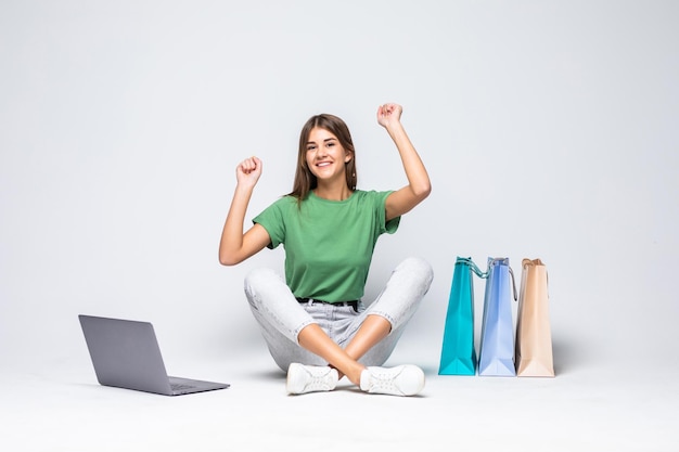 Young woman shopping online at home sitting besides row of shopping bags