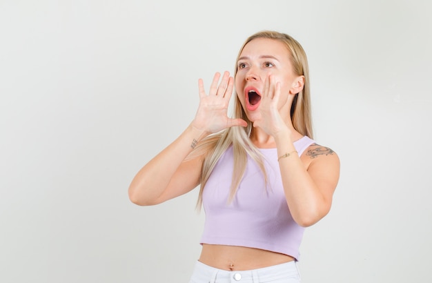 Young woman shouting with hands near mouth in singlet