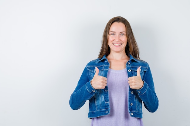 Free photo young woman showing double thumbs up in t-shirt, jacket and looking glad , front view.