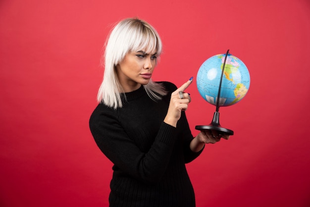 Free photo young woman showing a globe on a red background. high quality photo