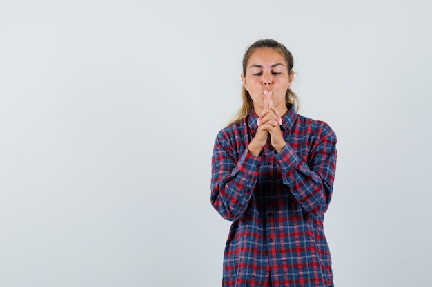 Young woman showing gun gesture on mouth in checked shirt and looking focused