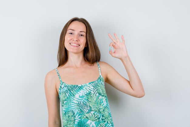 Young woman showing ok gesture and looking merry. front view.