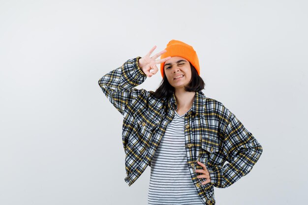 Young woman showing ok gesture in orange hat checkered shirt looking cute