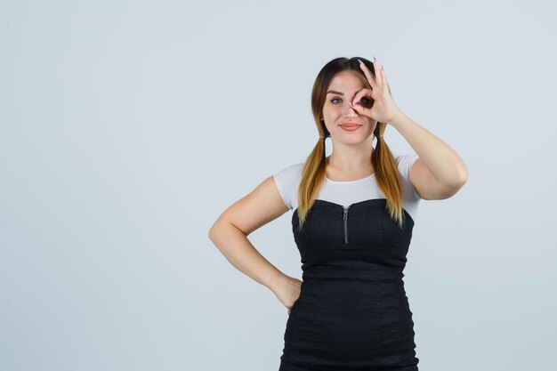 Young woman showing ok sign on eye