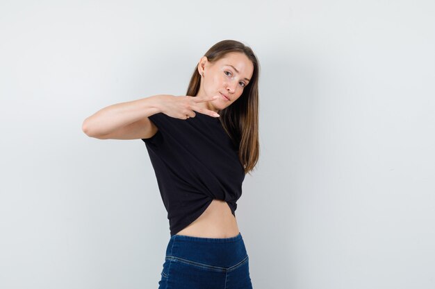 Young woman showing scissors gesture in black blouse and looking focused