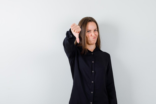 Young woman showing thumbs down and looking displeased