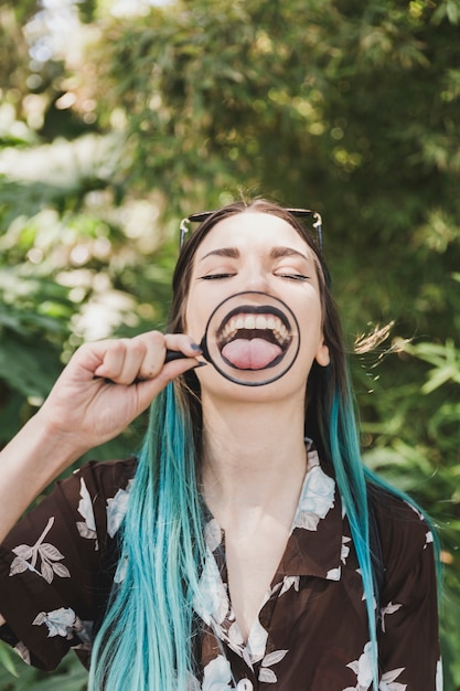 Free photo young woman showing tongue through magnifying glass