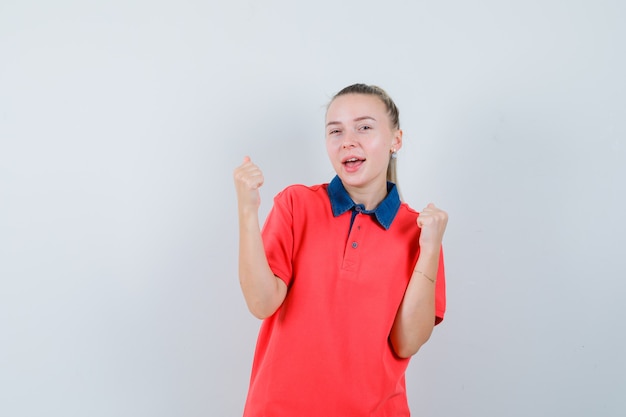 Young woman showing winner gesture in t-shirt and looking happy