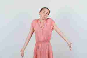 Free photo young woman shrugging and showing helpless gesture in striped dress , front view.