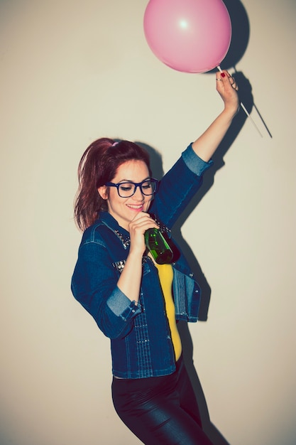 Free photo young woman singing and dancing with a balloon and a beer