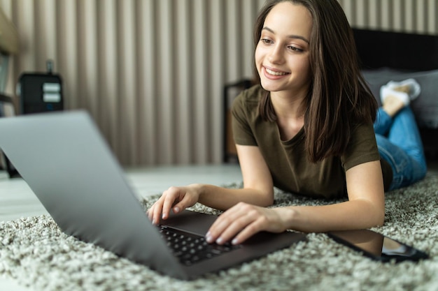 Free photo young woman sit carpet folded use laptop make work management project in room indoors