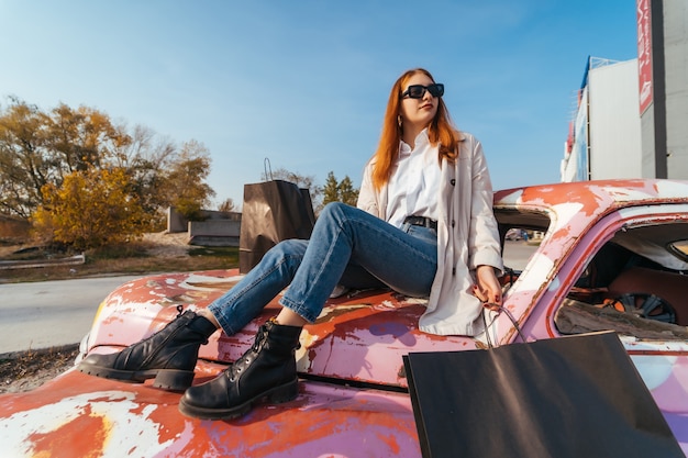 Young woman sits on an old decorated car