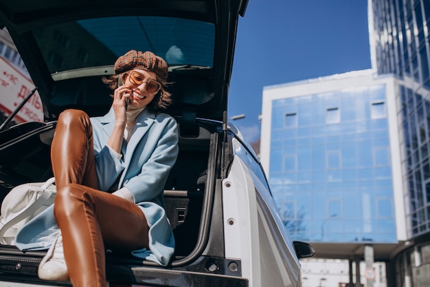 Young woman sitting in the back of the car talking on the phone