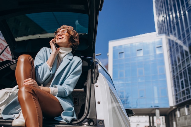 Young woman sitting in the back of the car talking on the phone