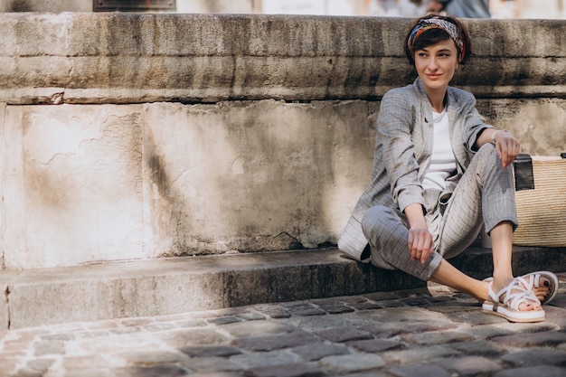 Free photo young woman sitting by the fountain