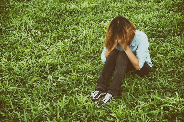 Young woman sitting on the grass crying