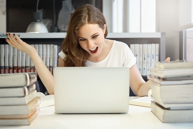 Free photo young woman sitting in library with laptop