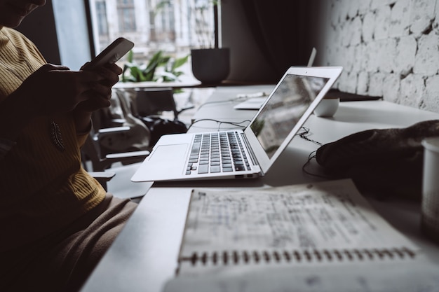 Free photo young woman sitting at office table with laptop.