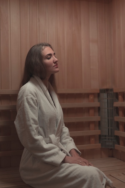 Young woman sitting relaxed in a wooden sauna