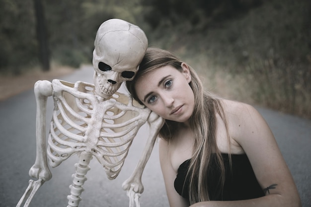 Free photo young woman sitting on road with skeleton