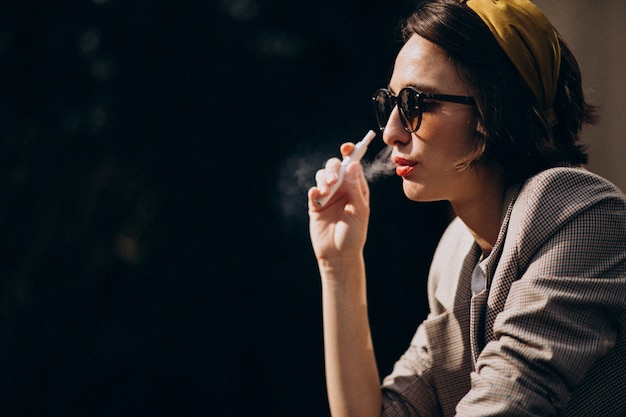 Free Photo young woman sitting and smoking ecigarette