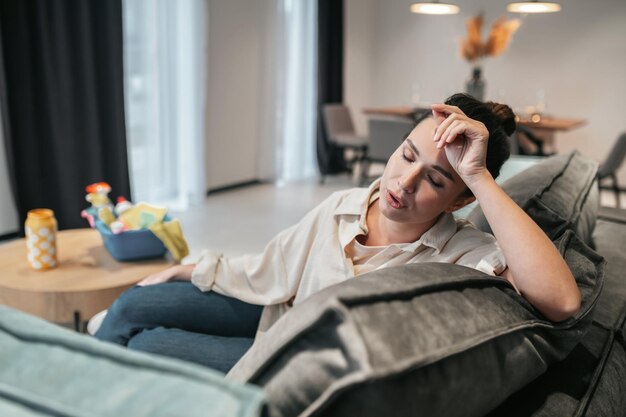 Young woman sitting on the sofa and looking tired