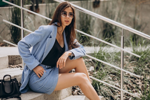 Young woman sitting on stairs in a blue suit