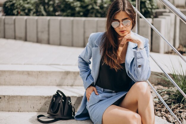 Young woman sitting on stairs in a blue suit