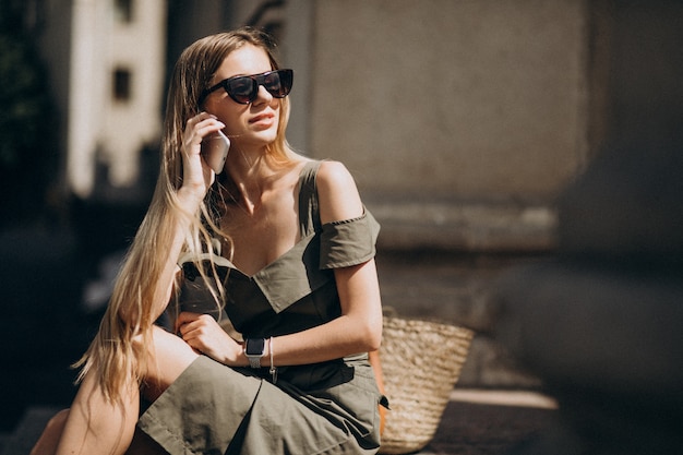 Free photo young woman sitting on the stairs and talking on the phone