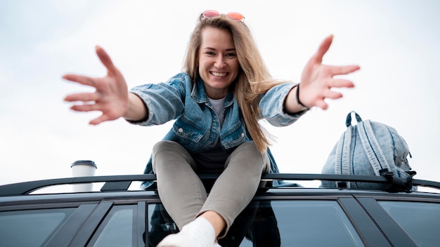 Young woman sitting on top of the car