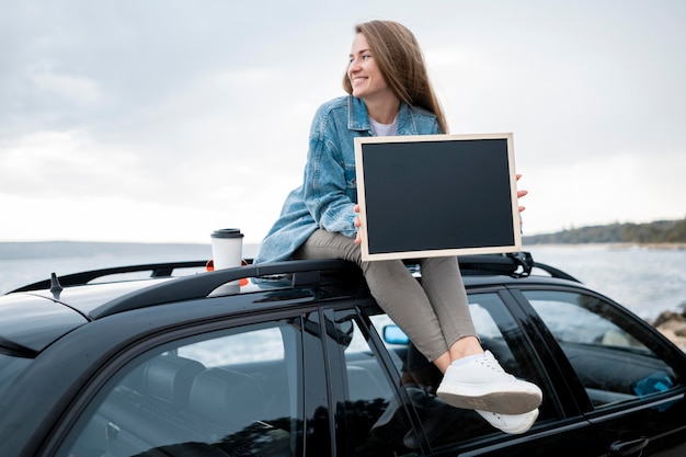 Young woman sitting on top of the car