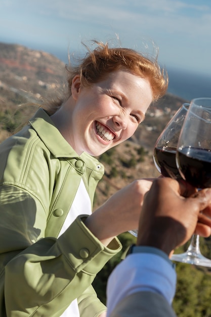 Free Photo young woman smiling and toasting with her friend during outdoor party