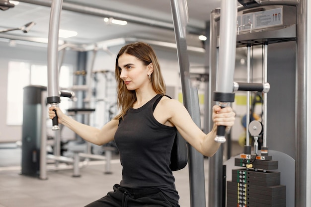 Young woman in sportswear doing excercisses with special equipment at gym