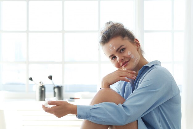 Young woman spreading facial cream. Skin care concept.