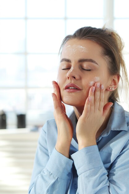 Free Photo young woman spreading facial cream. skin care concept.