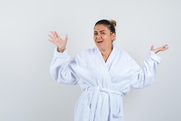 Free photo young woman spreading palms aside in bathrobe and looking happy