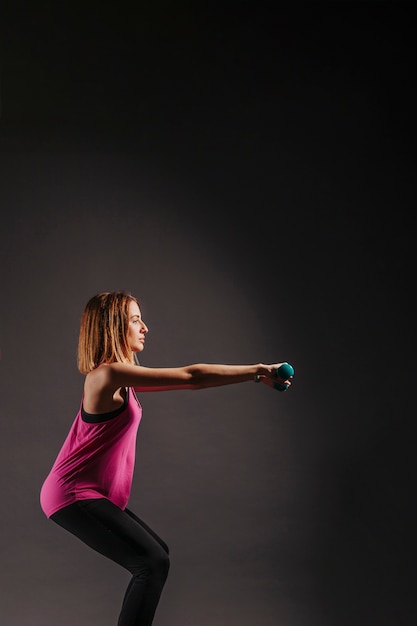 Young woman squatting with dumbbells