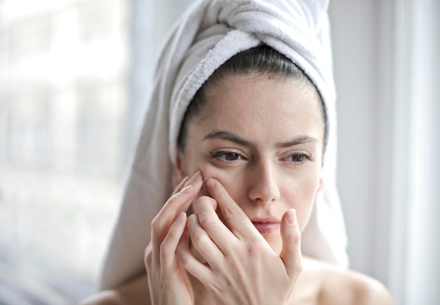 Young woman squeezes a pimple on her face