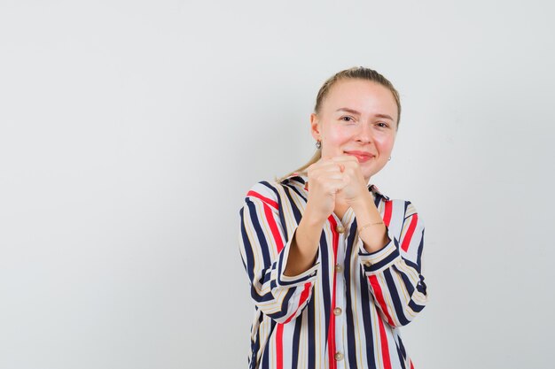 Young woman standing in fight gesture and looking optimistic